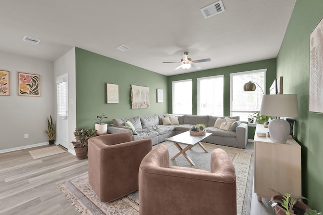 living room with visible vents, baseboards, and light wood-style floors