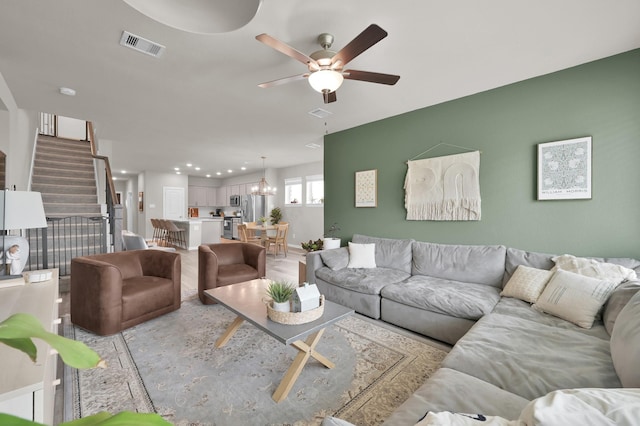 living area featuring recessed lighting, stairway, ceiling fan with notable chandelier, and visible vents