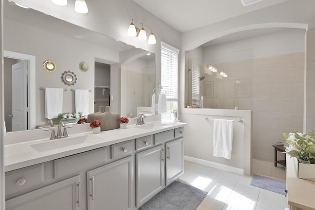 bathroom with double vanity, tile patterned flooring, a walk in shower, and a sink