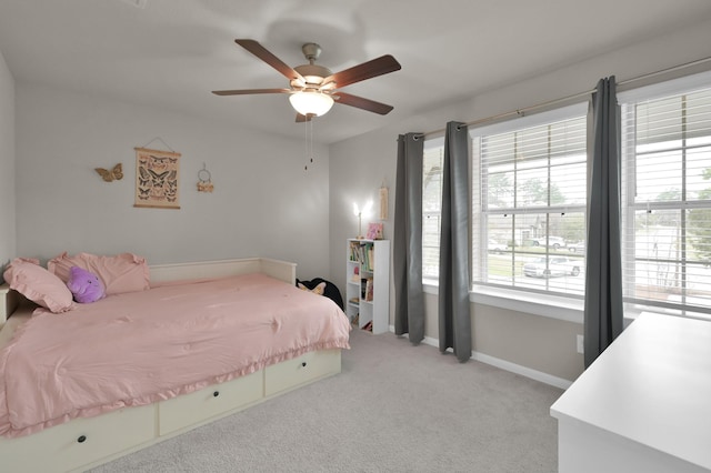 bedroom featuring ceiling fan, multiple windows, baseboards, and light carpet