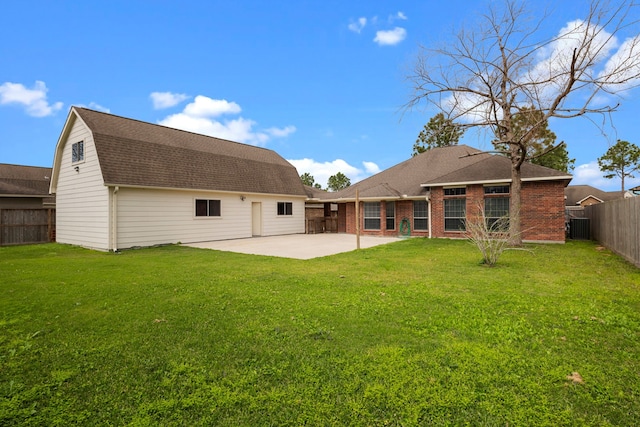 back of house with a yard, a gambrel roof, roof with shingles, and a patio area