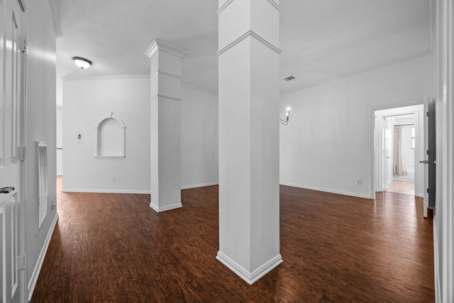 corridor featuring dark wood-style floors, baseboards, visible vents, decorative columns, and crown molding