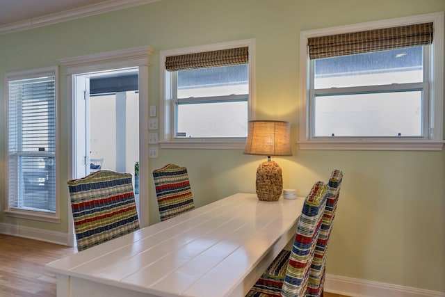 dining room featuring wood finished floors, baseboards, and ornamental molding