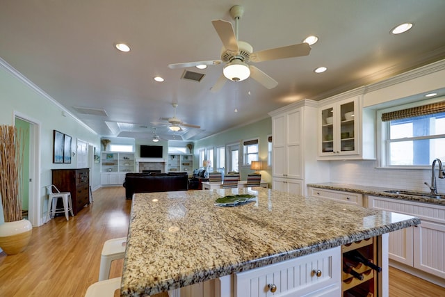 kitchen featuring a sink, visible vents, light wood-style floors, and crown molding