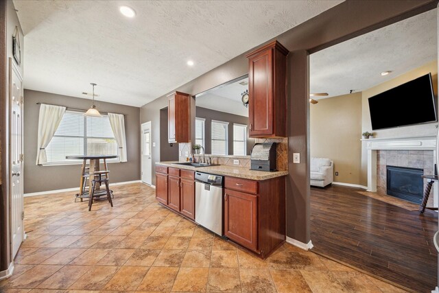 kitchen with a healthy amount of sunlight, dishwasher, a fireplace, and a sink