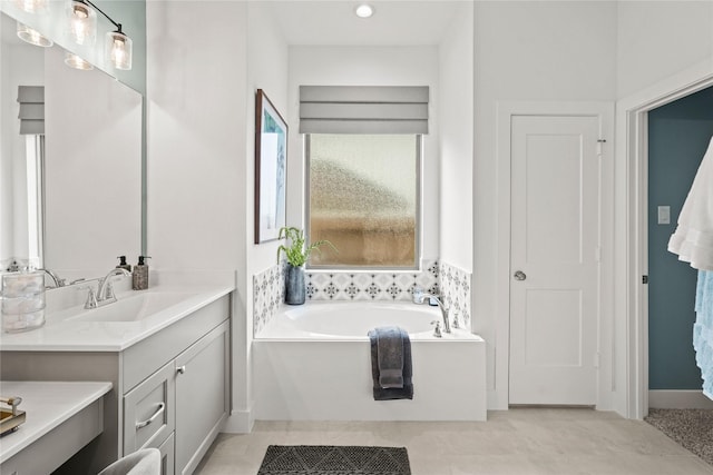 bathroom with a garden tub, vanity, and tile patterned flooring