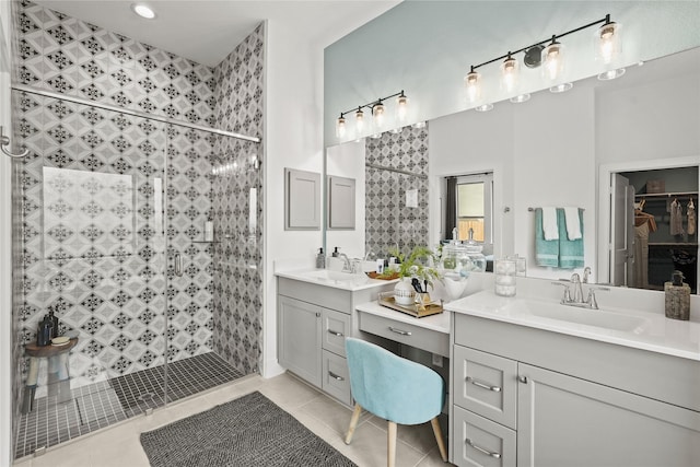 bathroom featuring tile patterned flooring, a shower stall, two vanities, and a sink