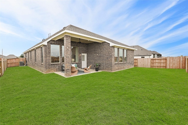 back of house featuring a yard, a patio area, brick siding, and a fenced backyard