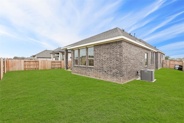 back of house featuring central air condition unit, a lawn, a fenced backyard, and brick siding