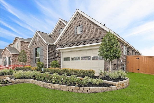 view of front of property with a garage, a standing seam roof, a front yard, metal roof, and brick siding