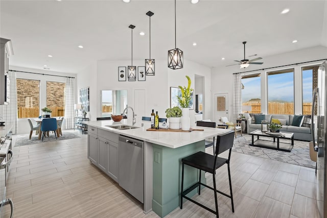 kitchen with open floor plan, a center island with sink, a breakfast bar, appliances with stainless steel finishes, and a sink