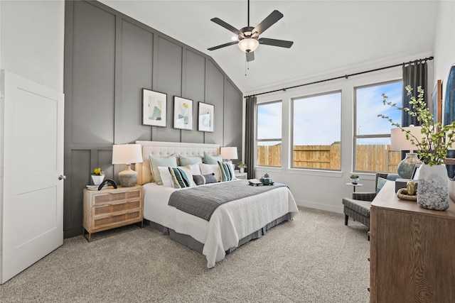 bedroom with lofted ceiling, light colored carpet, a ceiling fan, and a decorative wall