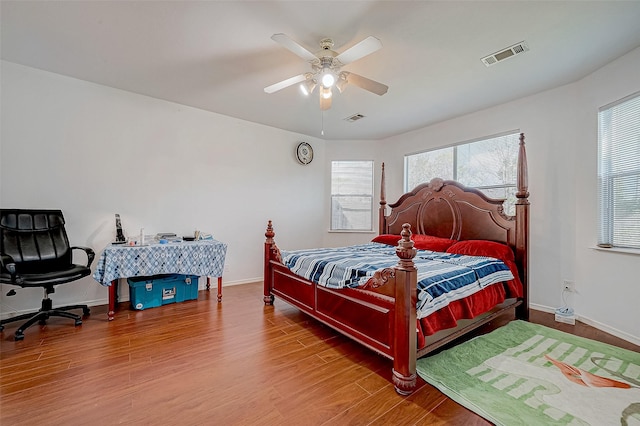 bedroom with wood finished floors, visible vents, and multiple windows