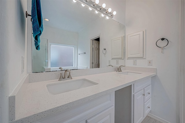 full bathroom with double vanity, a sink, and an enclosed shower