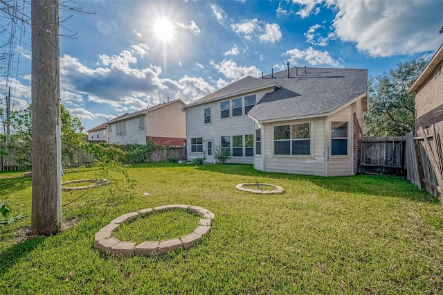 rear view of property with a yard, a shingled roof, and a fenced backyard