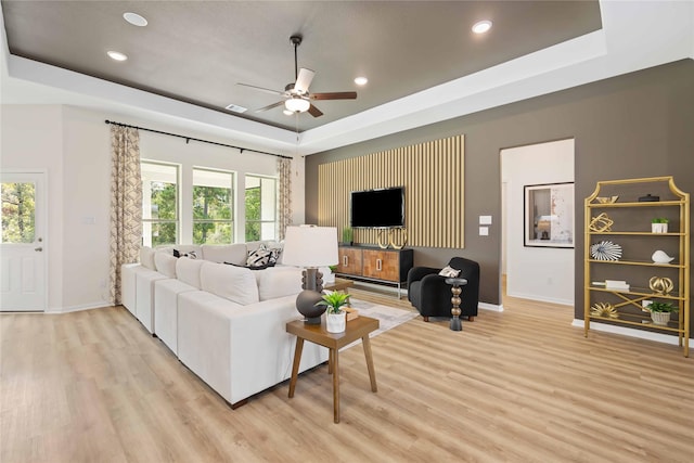 living room with a healthy amount of sunlight, light wood-type flooring, and a tray ceiling