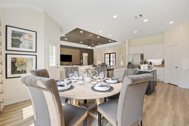 dining room featuring light wood finished floors, visible vents, recessed lighting, and a raised ceiling