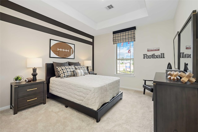 bedroom with a tray ceiling, light carpet, baseboards, and visible vents