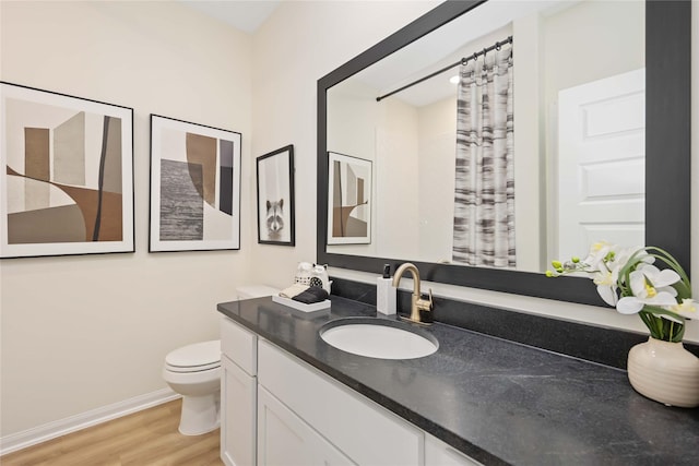 bathroom featuring vanity, toilet, wood finished floors, and baseboards