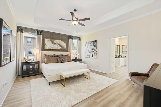 bedroom with a tray ceiling, multiple windows, light wood finished floors, and ornamental molding