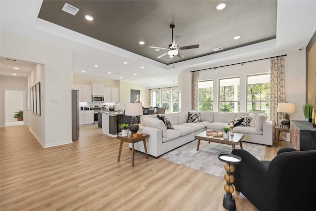 living area featuring visible vents, recessed lighting, light wood-type flooring, and a raised ceiling