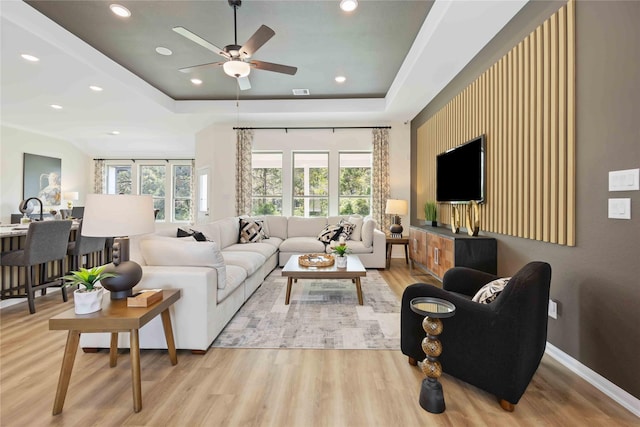 living room with recessed lighting, a raised ceiling, and light wood finished floors