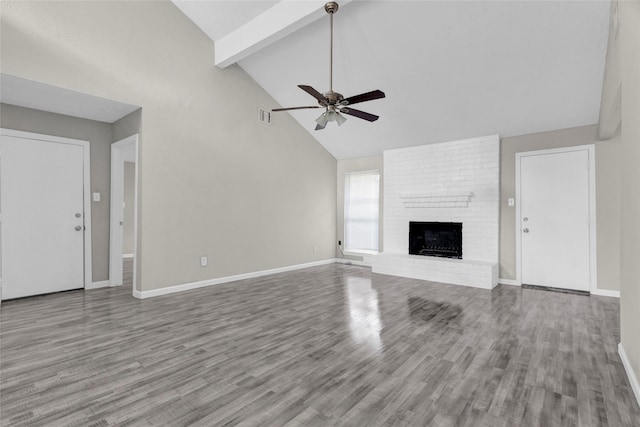 unfurnished living room with beam ceiling, visible vents, a fireplace, and wood finished floors