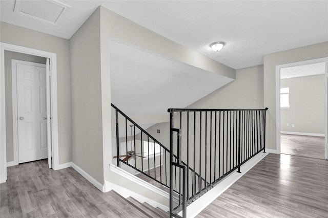 staircase with baseboards, attic access, and wood finished floors