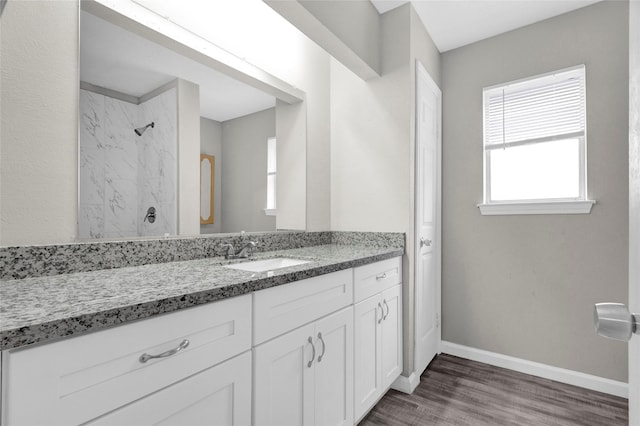 full bathroom with vanity, wood finished floors, a shower, and baseboards