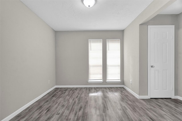 spare room featuring baseboards, a textured ceiling, and wood finished floors