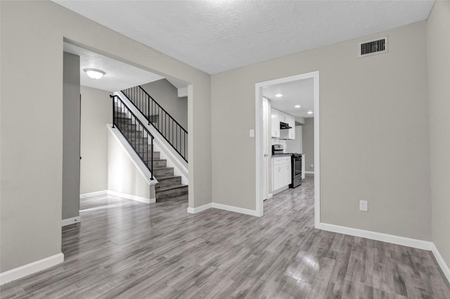 empty room featuring visible vents, stairs, baseboards, and wood finished floors