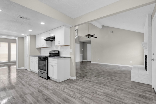 kitchen featuring stainless steel gas stove, white cabinetry, light wood-style floors, ceiling fan, and vaulted ceiling with beams