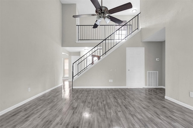 unfurnished living room with wood finished floors, visible vents, and baseboards