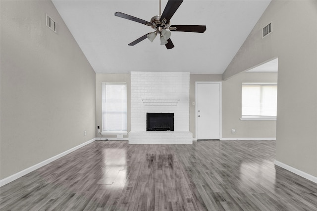 unfurnished living room with visible vents, baseboards, a brick fireplace, and wood finished floors