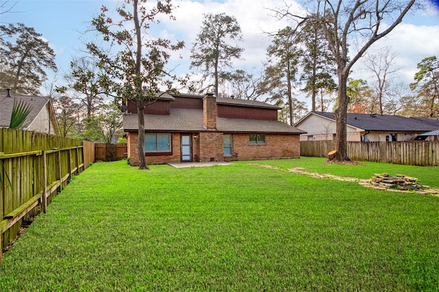 back of house featuring brick siding, a lawn, a shingled roof, and a fenced backyard