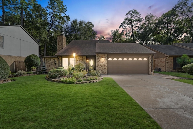 view of front facade with brick siding, concrete driveway, a chimney, a yard, and an attached garage