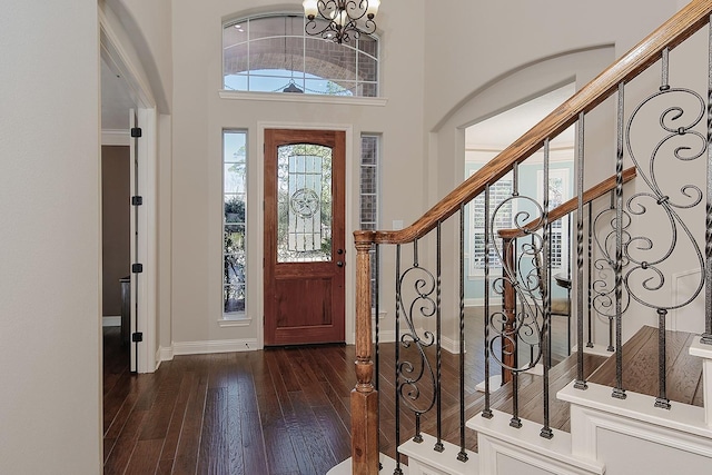 foyer with stairway, baseboards, dark wood finished floors, and a chandelier