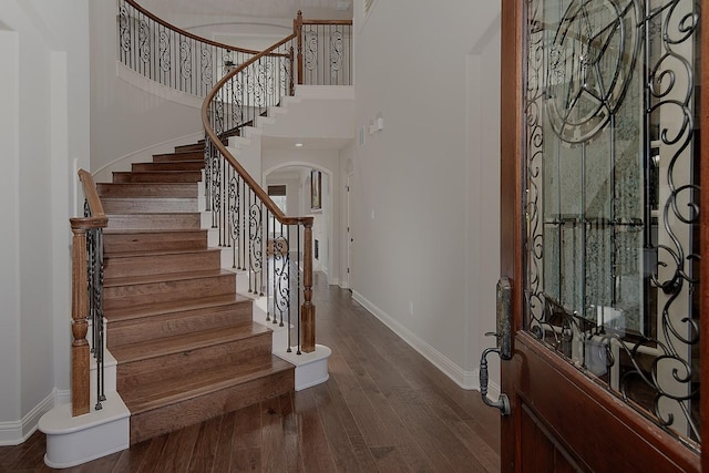 foyer entrance with dark wood finished floors, stairway, a high ceiling, and baseboards