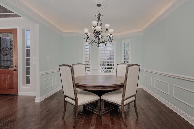 dining room with dark wood finished floors, a decorative wall, crown molding, and an inviting chandelier