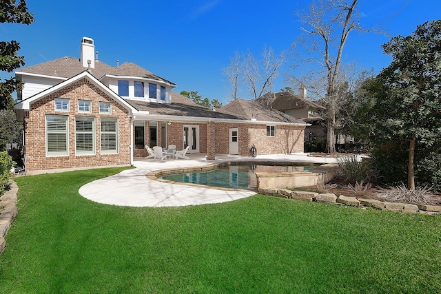 rear view of property featuring brick siding, an outdoor pool, a patio area, and a lawn