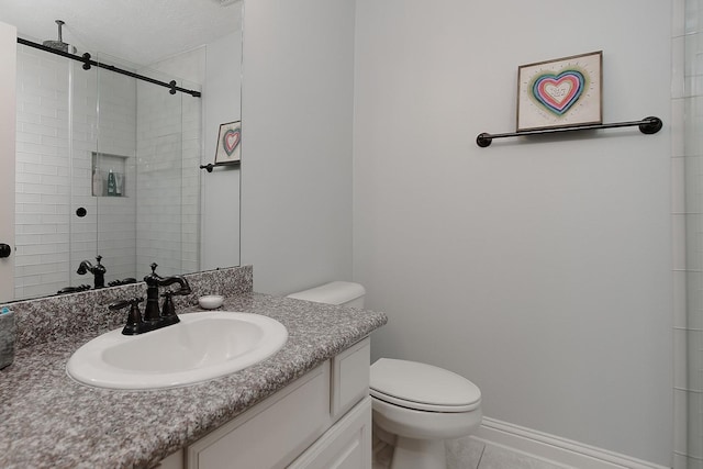 bathroom featuring tile patterned flooring, baseboards, toilet, tiled shower, and vanity