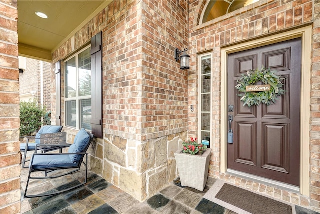 entrance to property with covered porch and brick siding