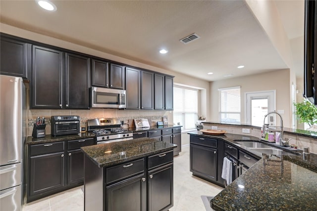 kitchen featuring dark stone countertops, visible vents, a toaster, stainless steel appliances, and tasteful backsplash