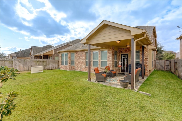 back of house with a patio area, a fenced backyard, brick siding, and a lawn