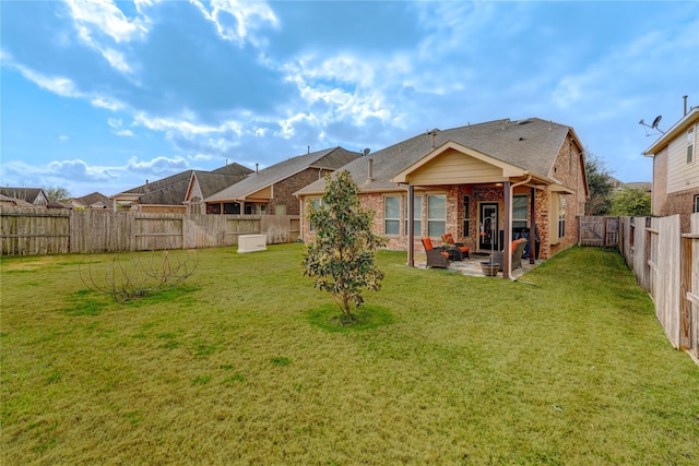 rear view of property with a patio, roof with shingles, a yard, a fenced backyard, and brick siding