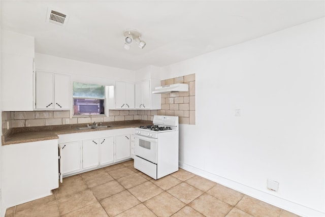 kitchen with dark countertops, visible vents, under cabinet range hood, white range with gas stovetop, and decorative backsplash