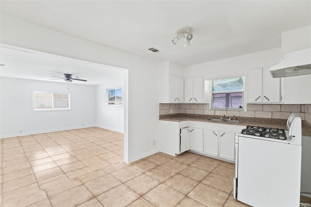 kitchen with a sink, gas range gas stove, tasteful backsplash, and white cabinetry