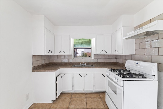 kitchen with under cabinet range hood, white gas range, decorative backsplash, white cabinets, and a sink