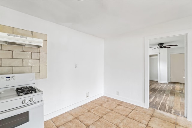 kitchen featuring a ceiling fan, baseboards, gas range gas stove, light tile patterned flooring, and under cabinet range hood