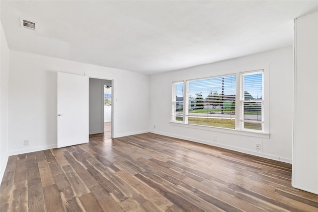 unfurnished room with visible vents, baseboards, and wood finished floors